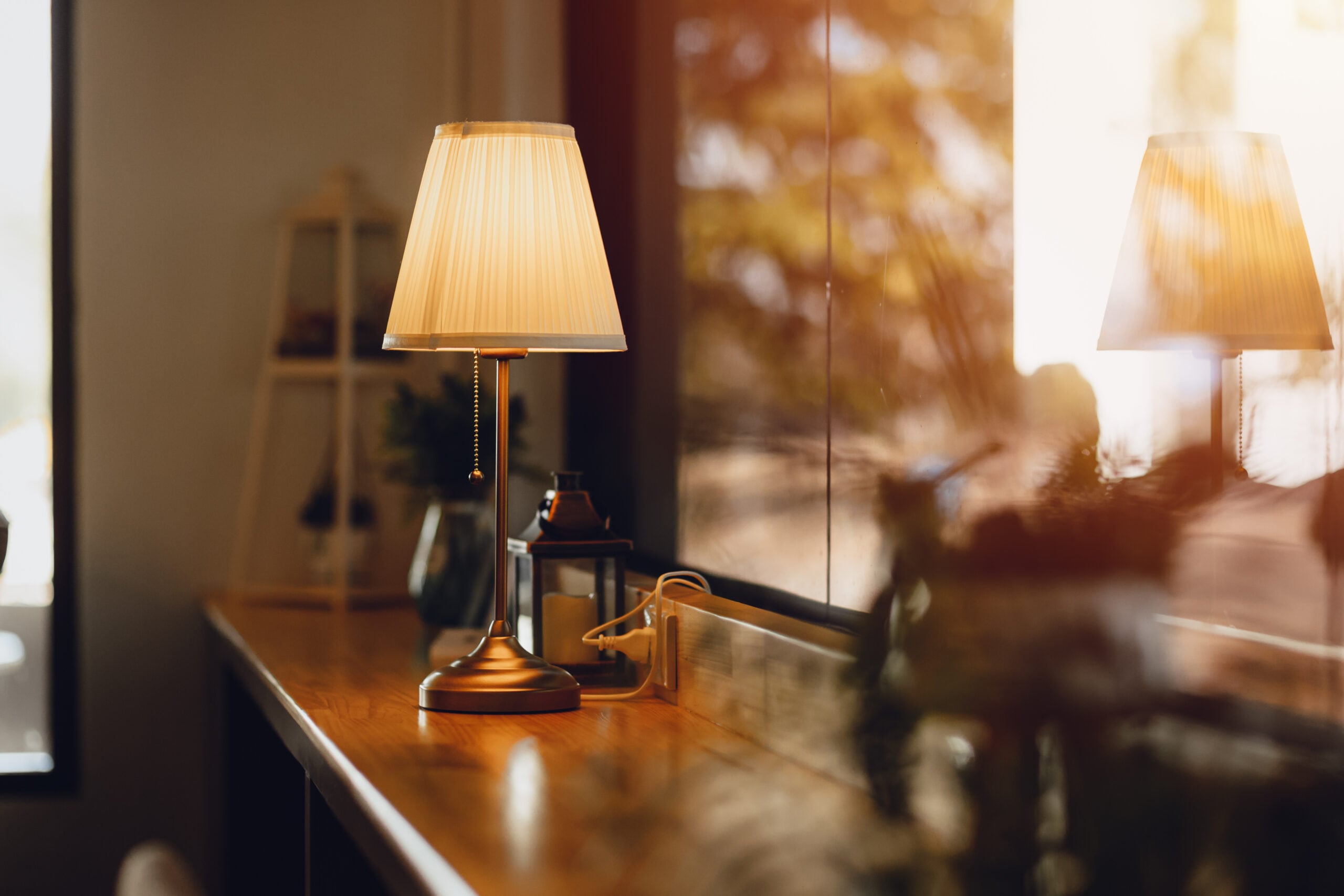 A warm table lamp glowing in the corner of a cozy home at dusk