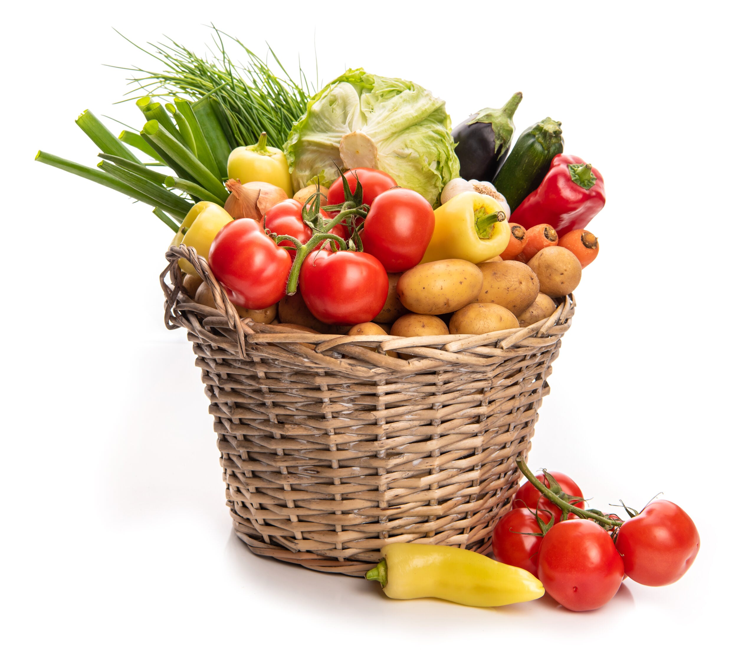 A large basket of freshly harvested garden vegetables including tomatoes and zucchini