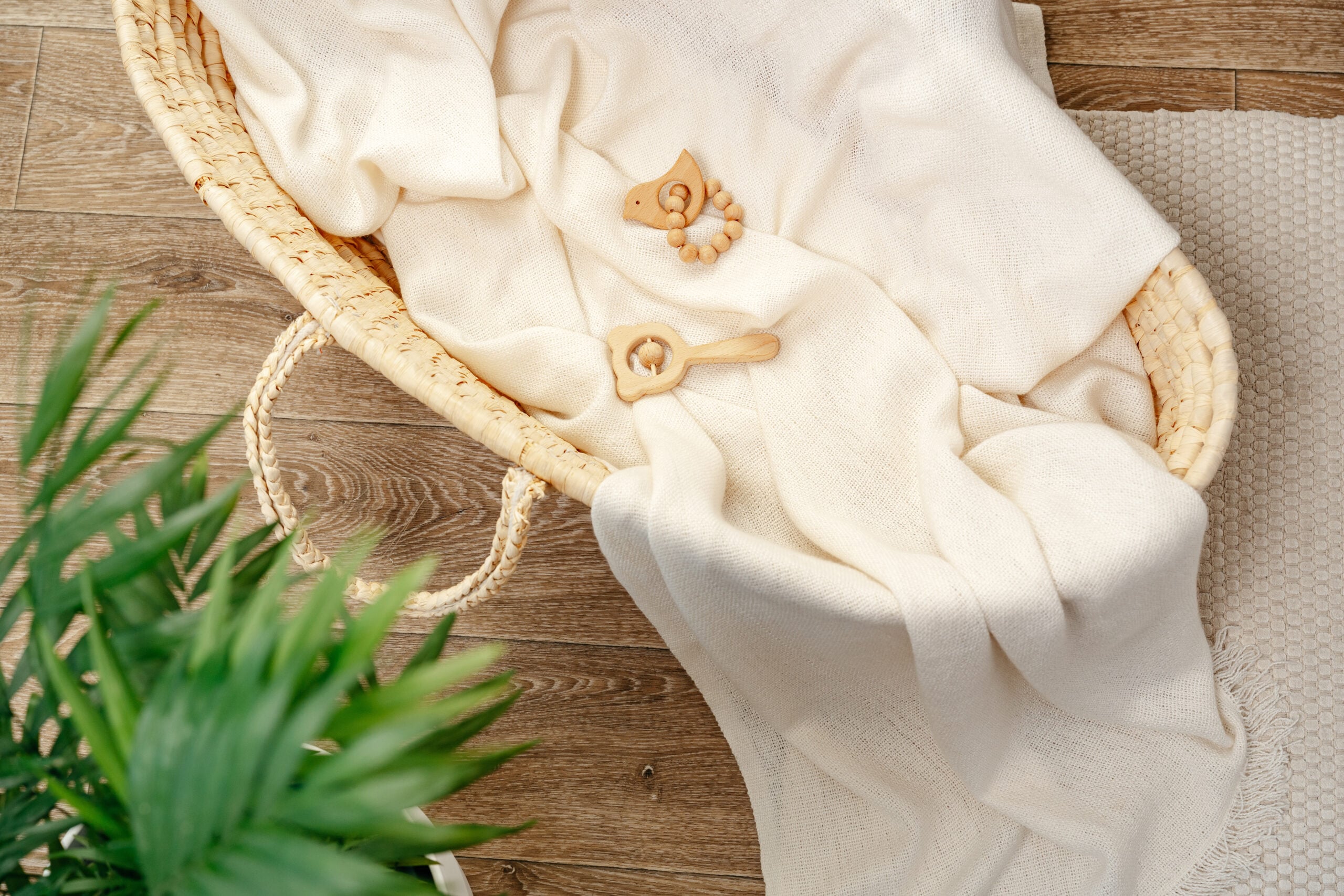 A neutral nursery corner with a muslin blanket and simple wooden toys