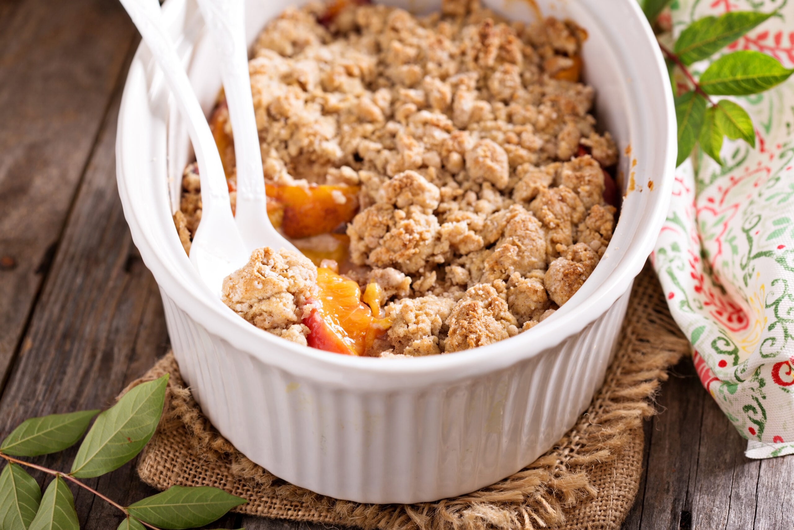 Peach crisp with an oat crumble topping in a white baking dish