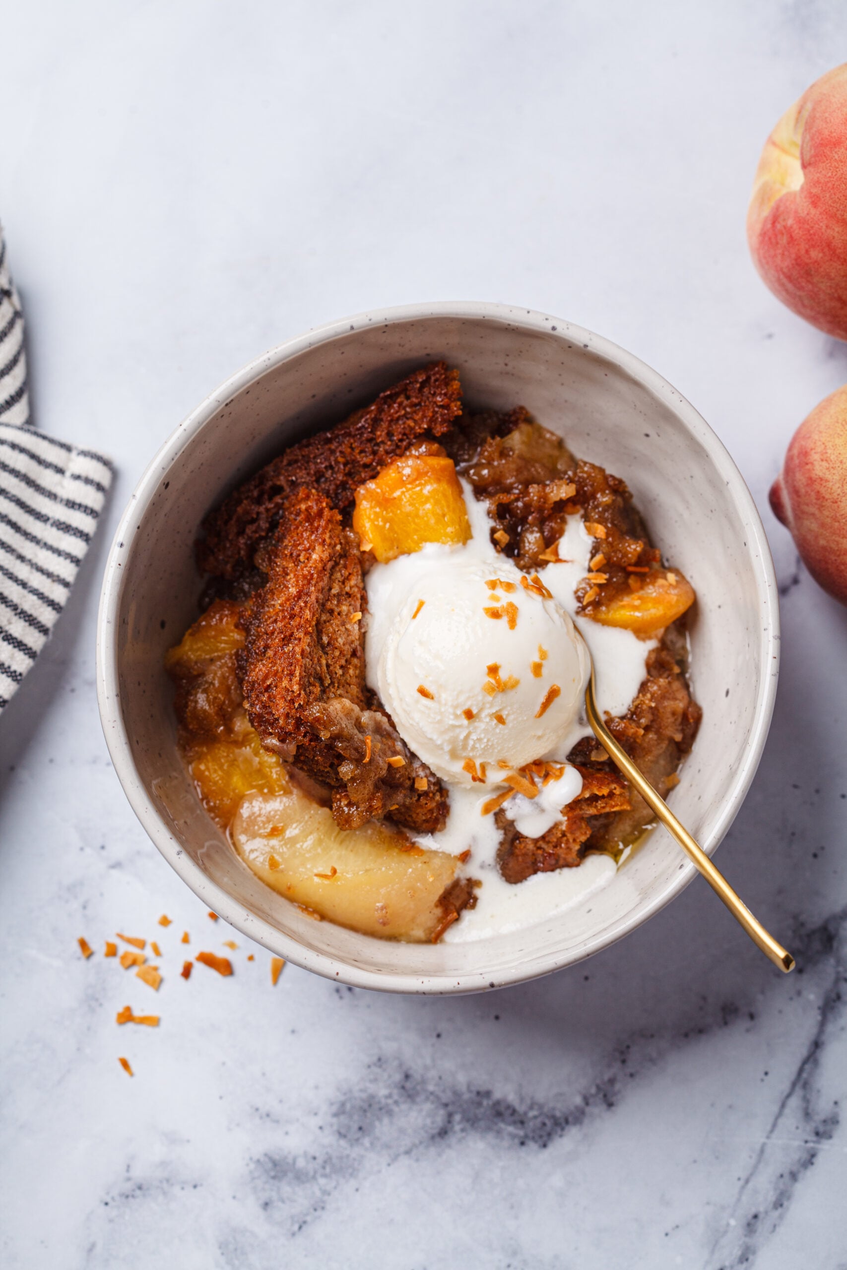 Warm peach crisp served with a scoop of vanilla ice cream melting on top