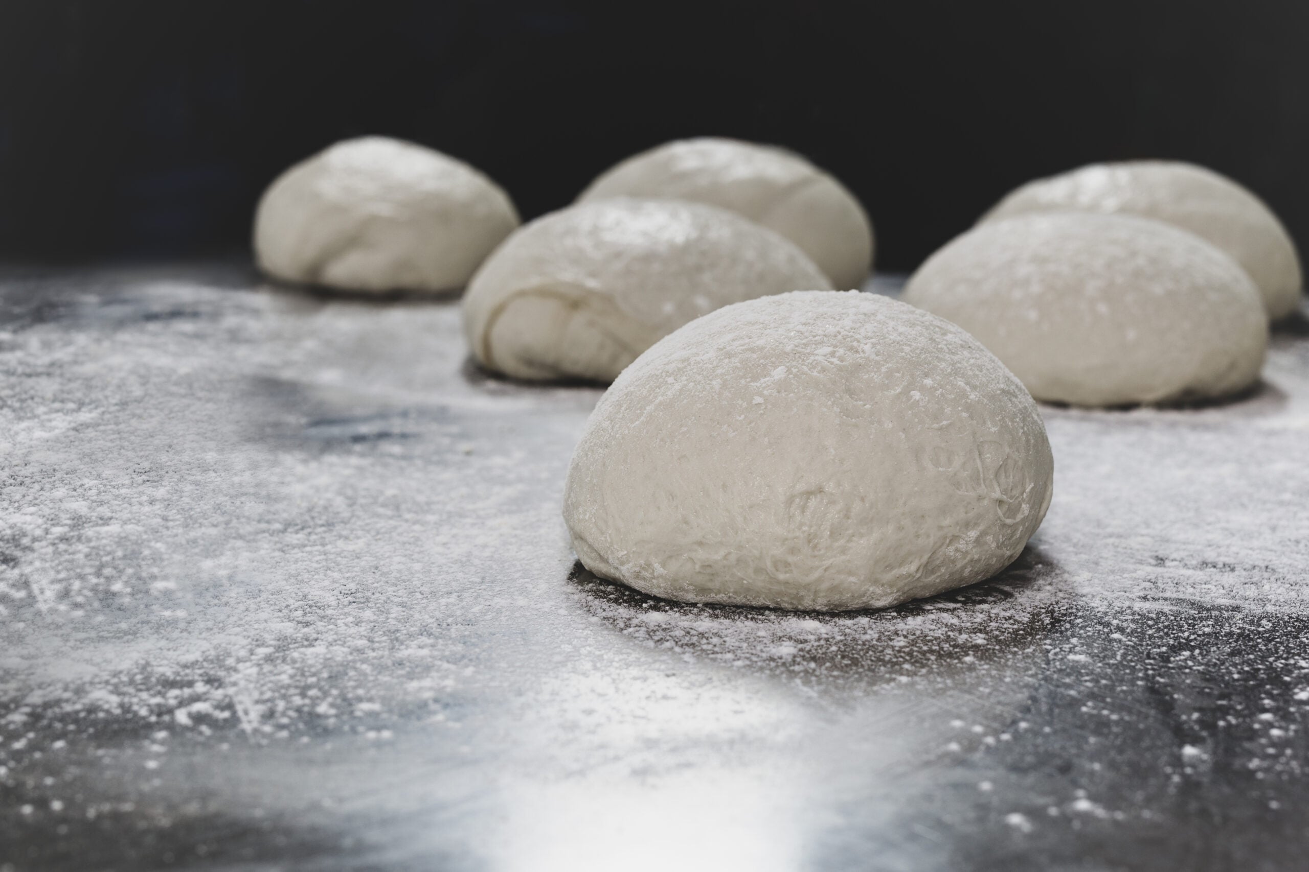 A ball of homemade pizza dough resting on a floured surface