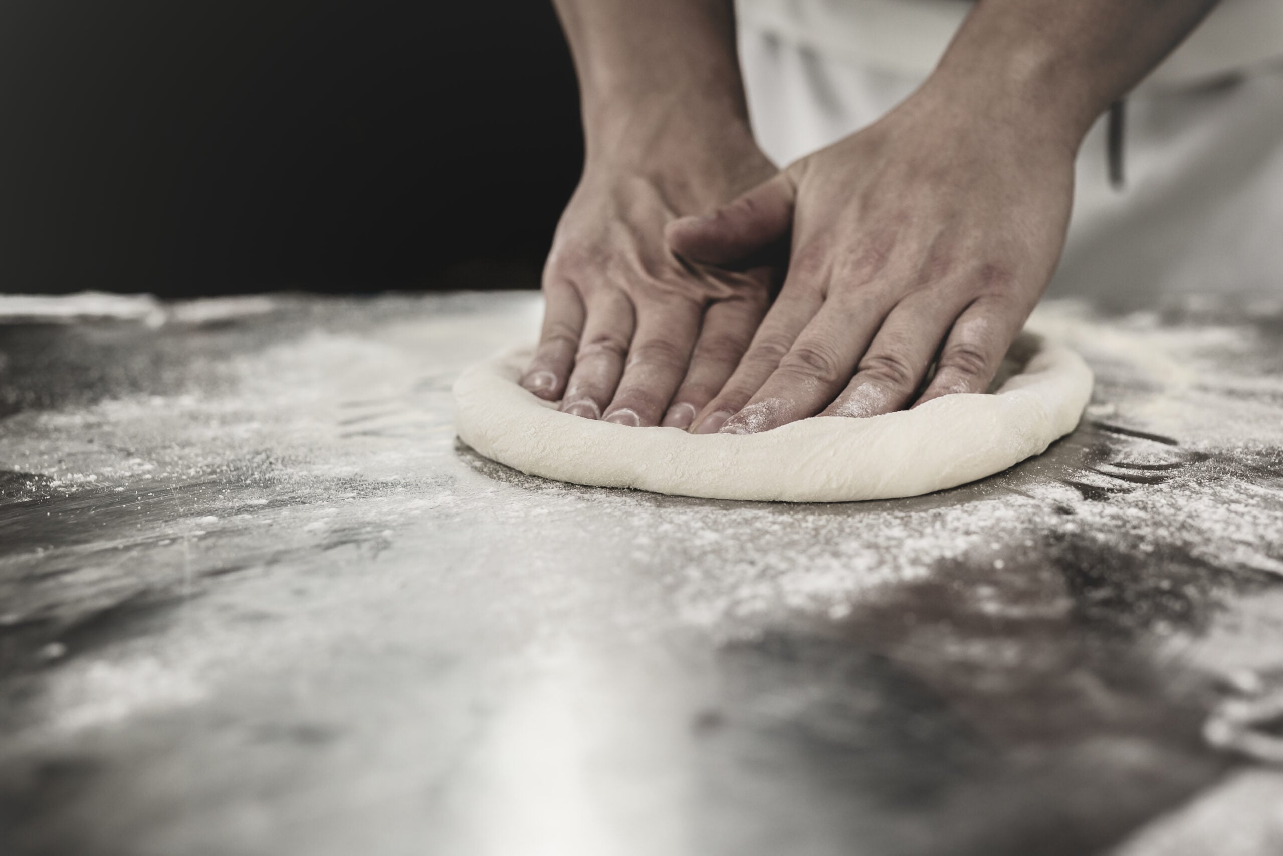 Hands kneading homemade pizza dough on a floured surface
