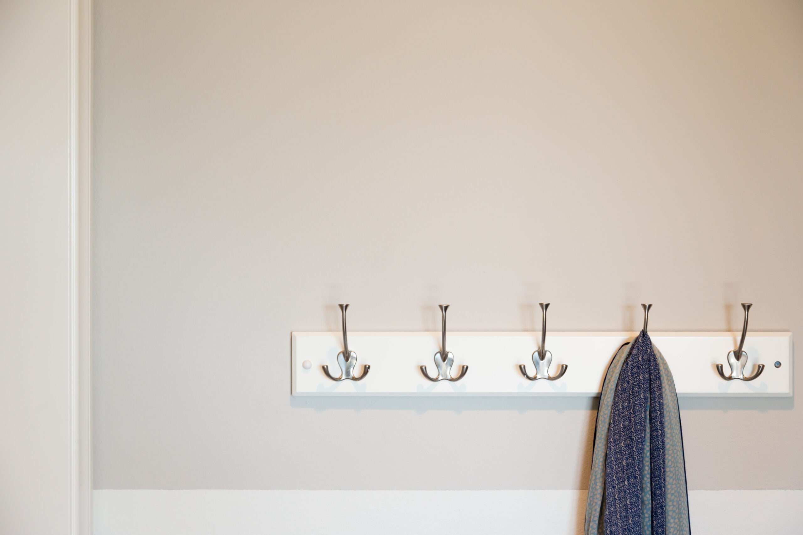 Coats and a scarf hanging on wall hooks by the door, a simple entryway spot where everything has a place