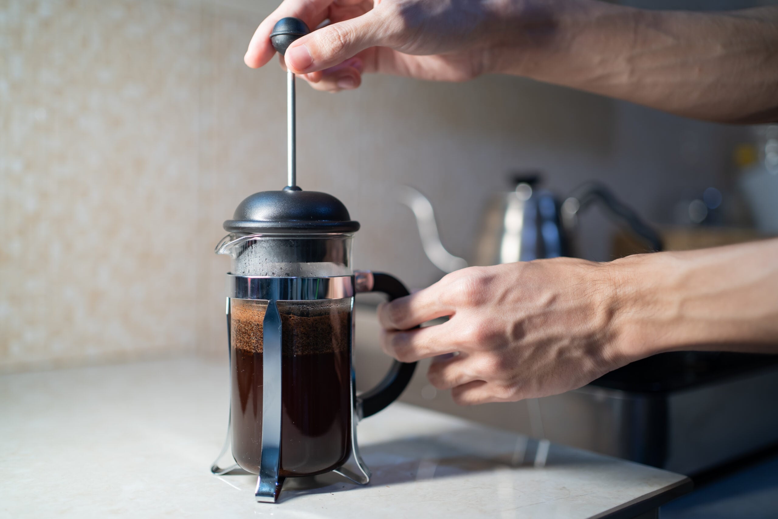 Making coffee slowly in a glass French press on a kitchen counter