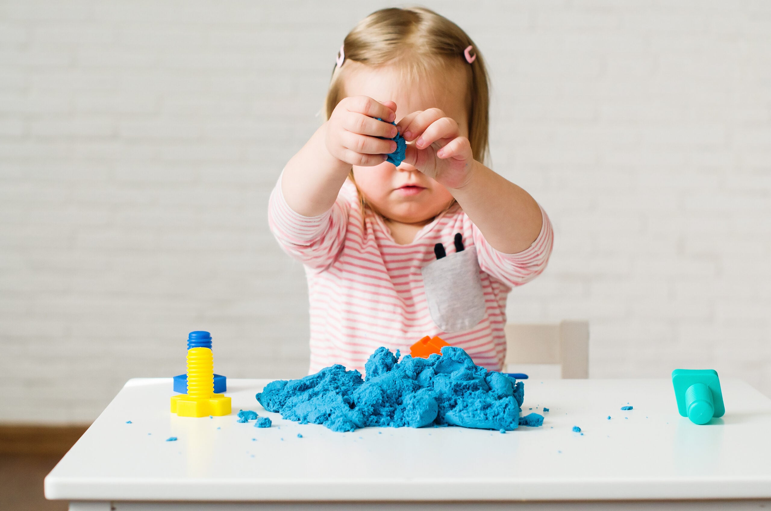 Small hands playing with kinetic sand as a quiet at-home activity