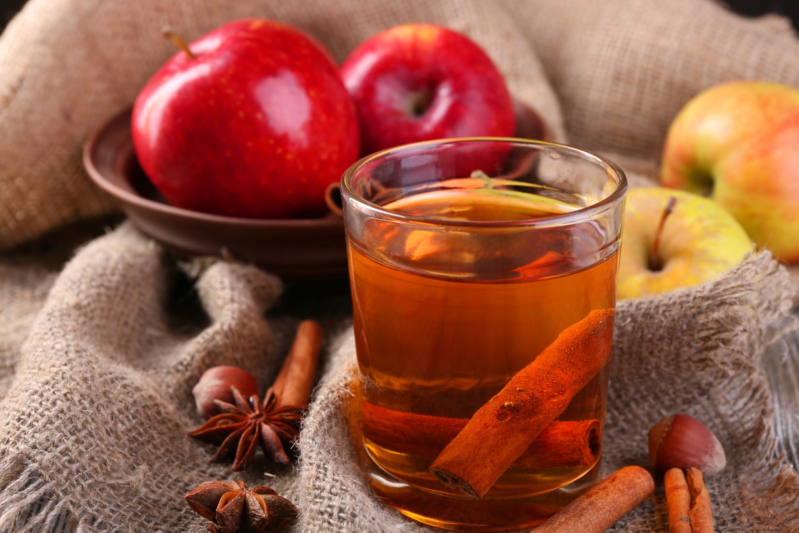 Fresh apple cider with cinnamon sticks and apples, ready to be simmered down for apple cider donuts