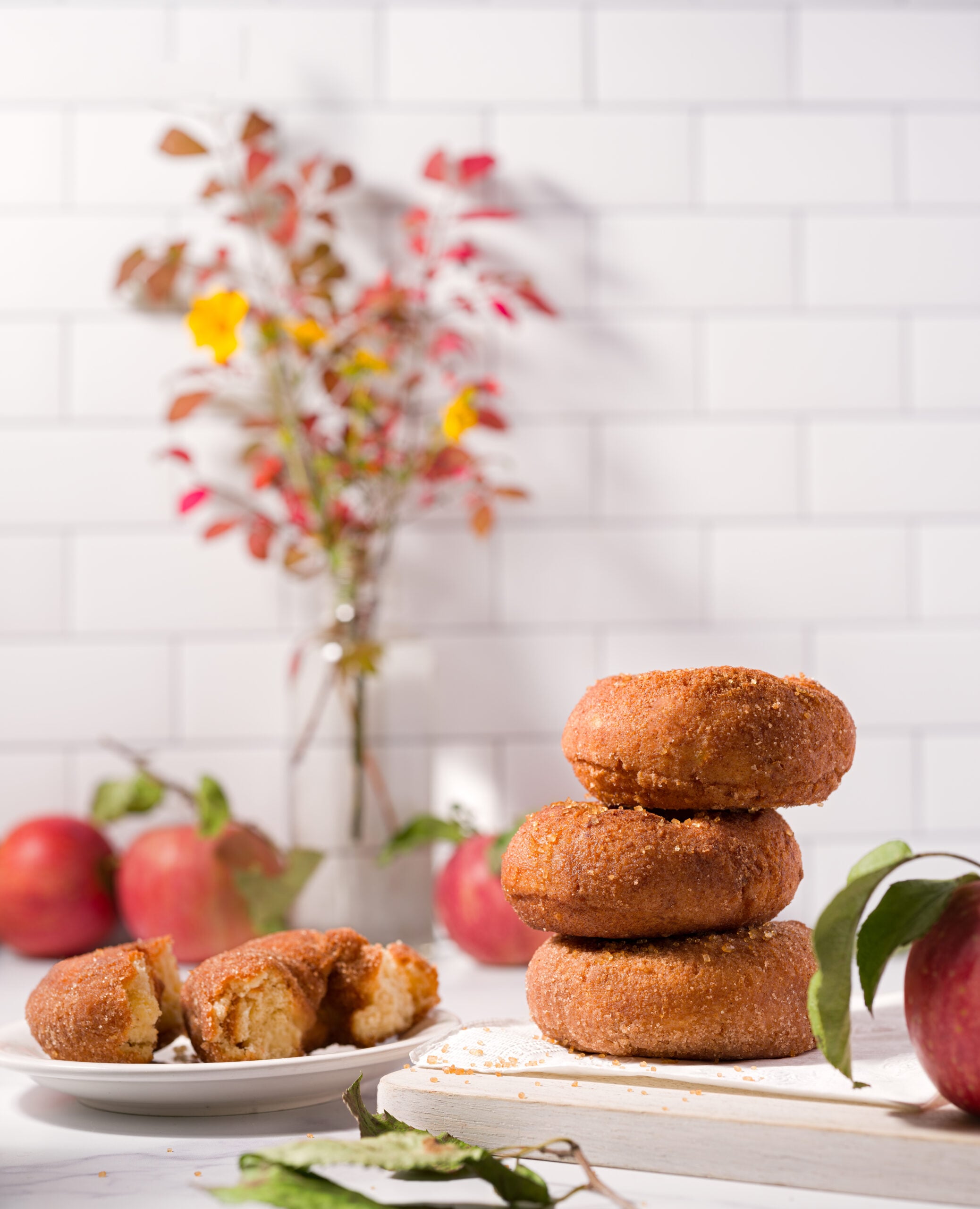 Apple cider donuts on a plate with fresh picked apples in a farmhouse kitchen