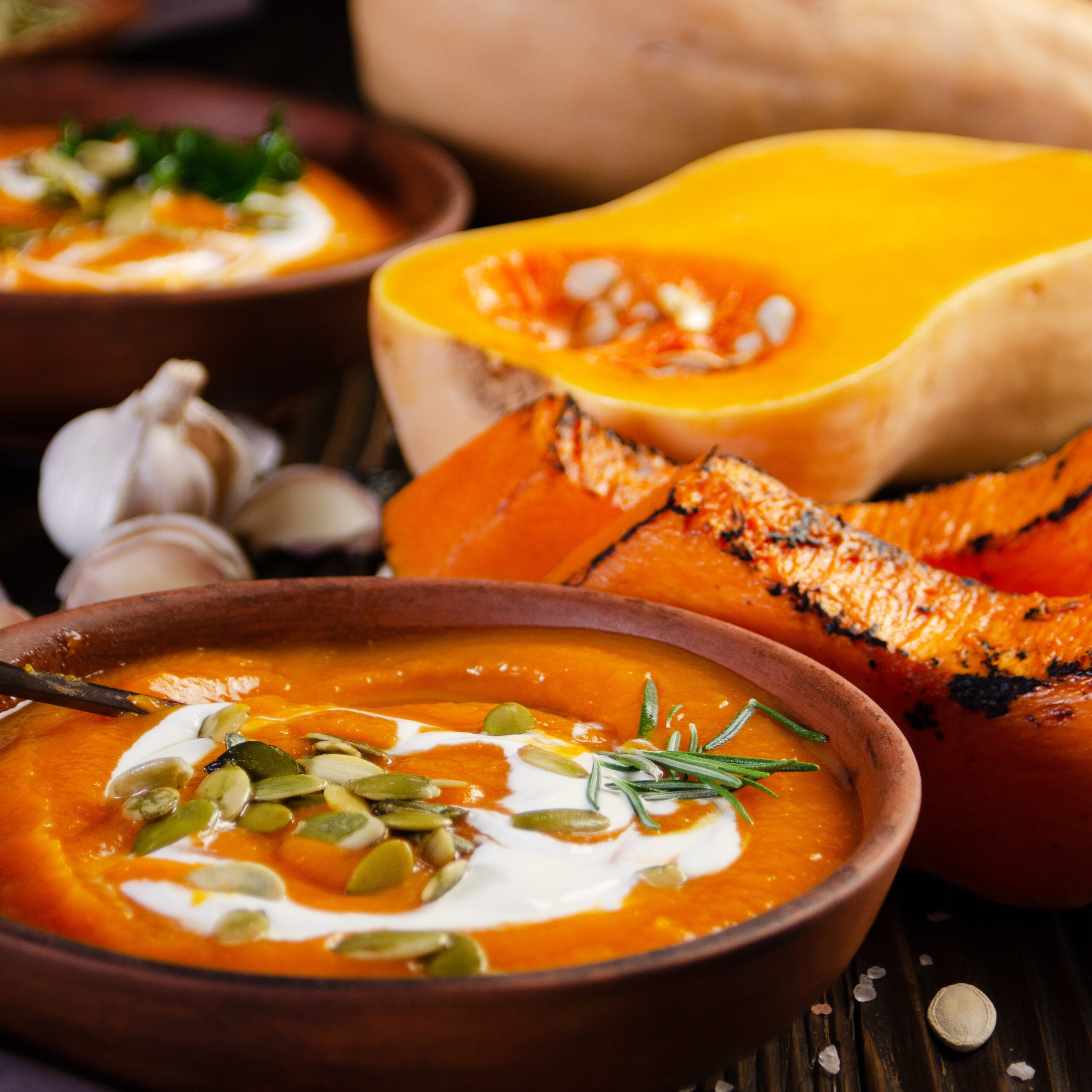 Butternut squash soup in a clay bowl with toasted sourdough bread and pumpkin seeds