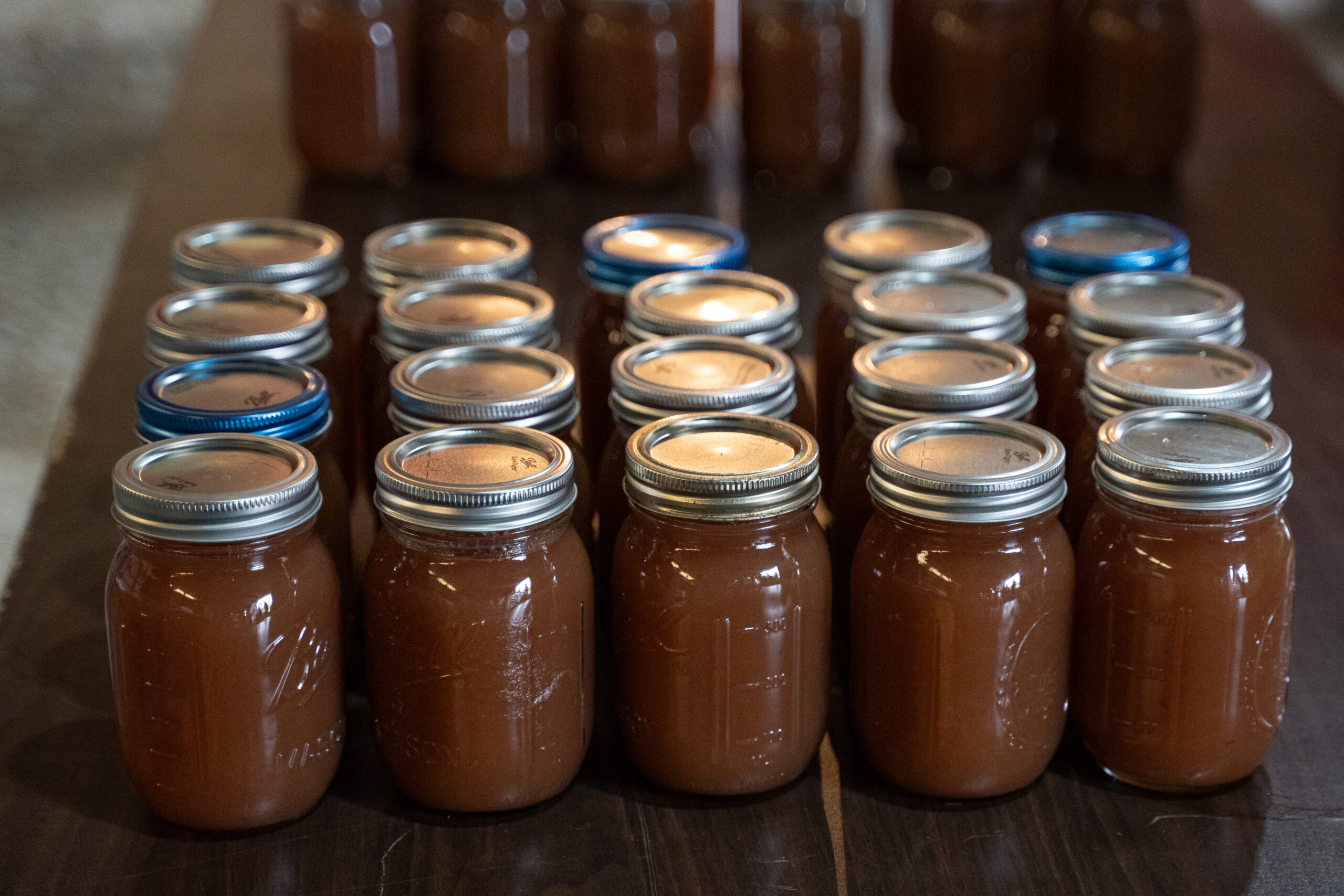 Pint jars of dark homemade crockpot apple butter cooling on a table