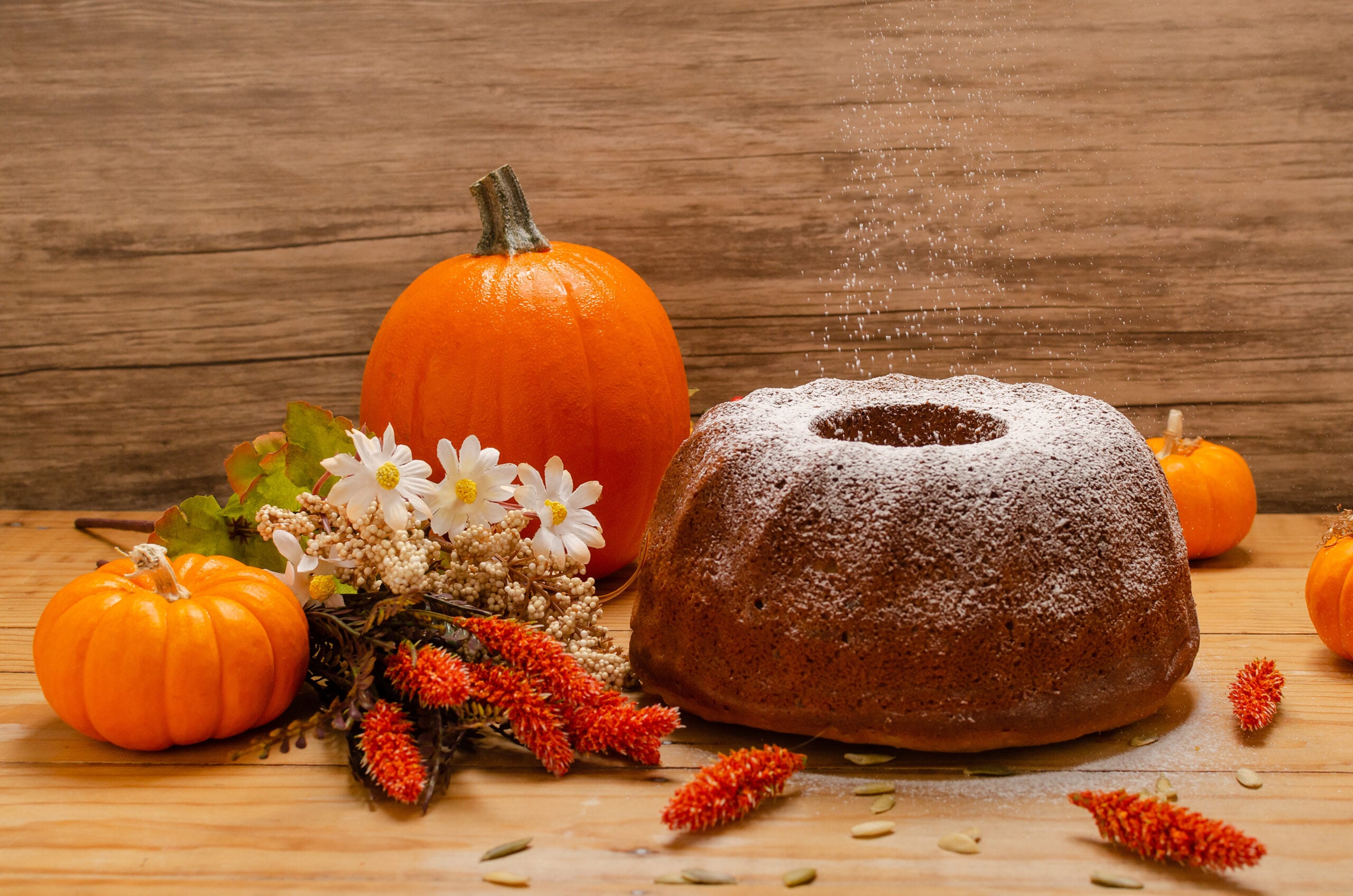 Whole loaf of homemade pumpkin bread cooling on a wooden table with autumn decor