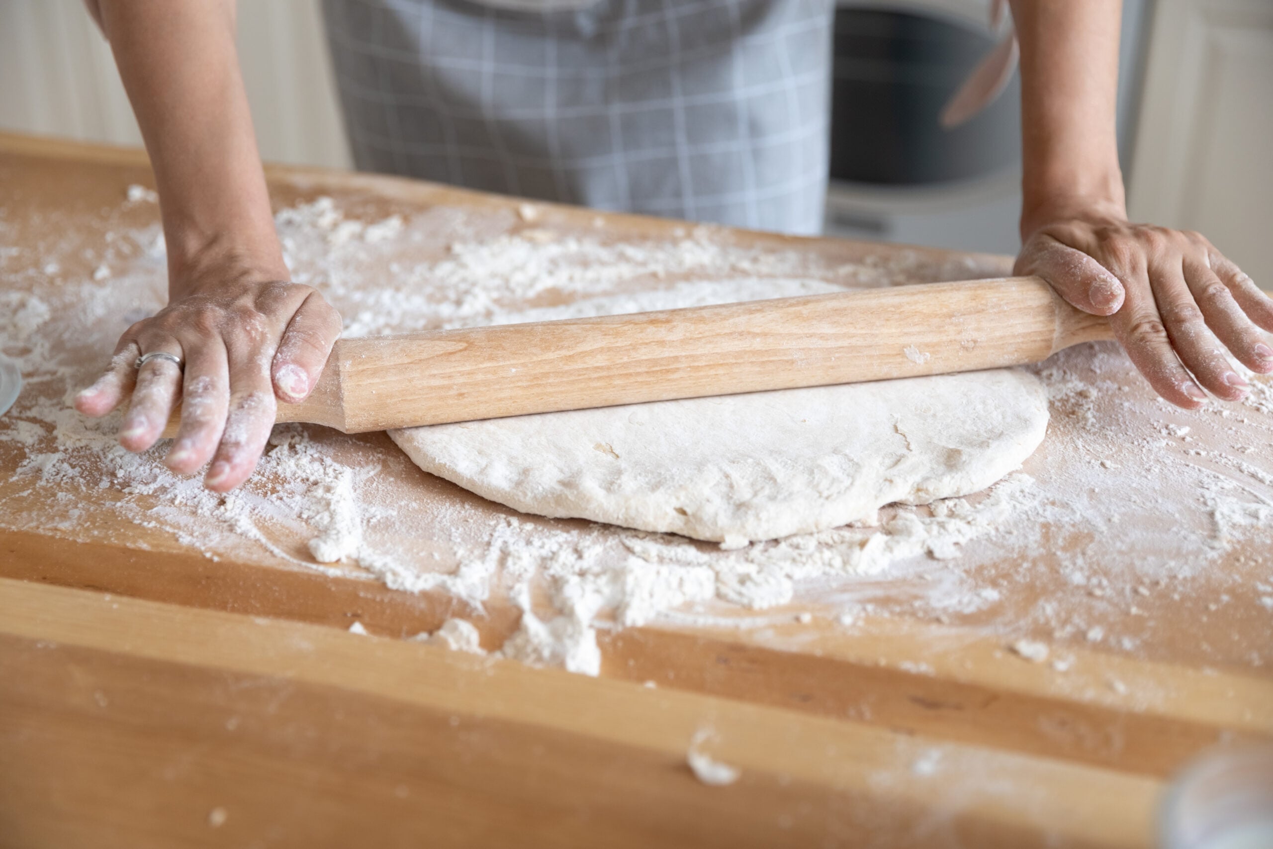 Rolling out all butter pie crust dough with a wooden rolling pin on a floured counter