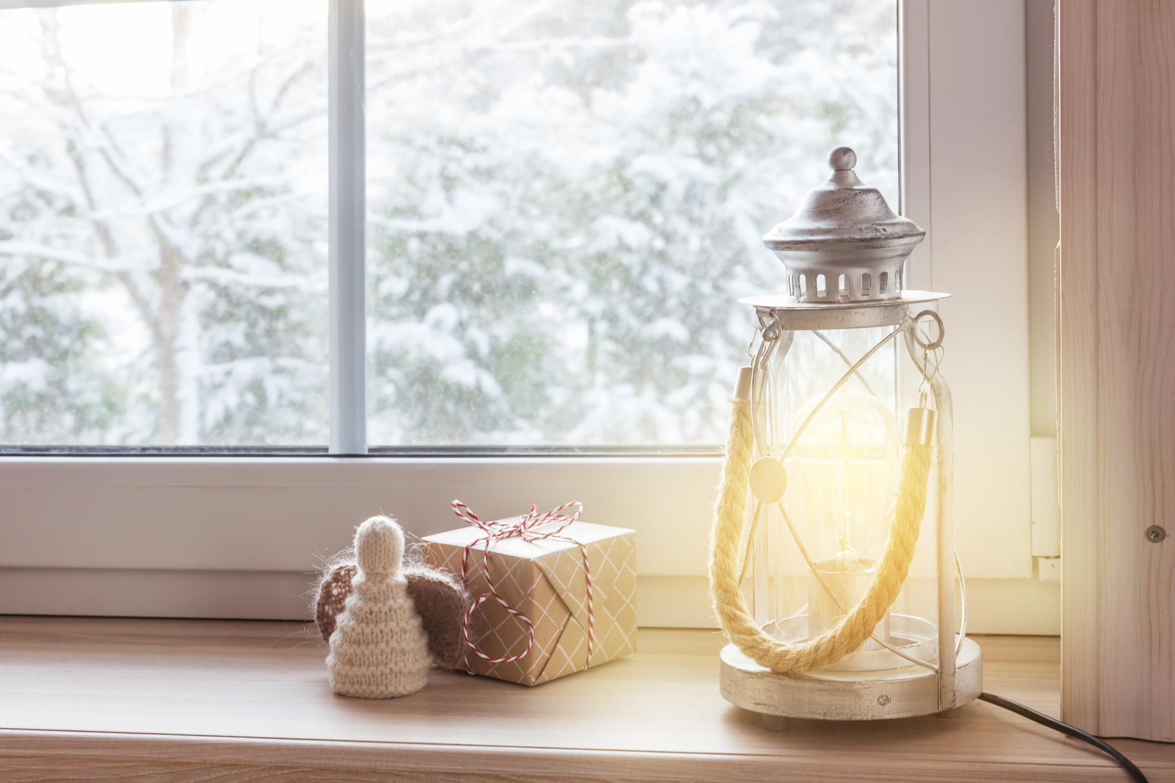 Burning candles and small lights on a windowsill on a dark winter afternoon