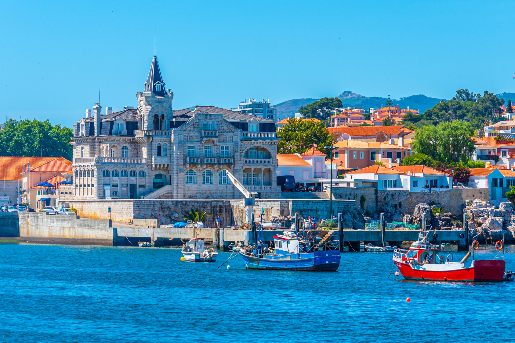 The marina at Cascais, Portugal, with pastel buildings and the Seixas palace behind it