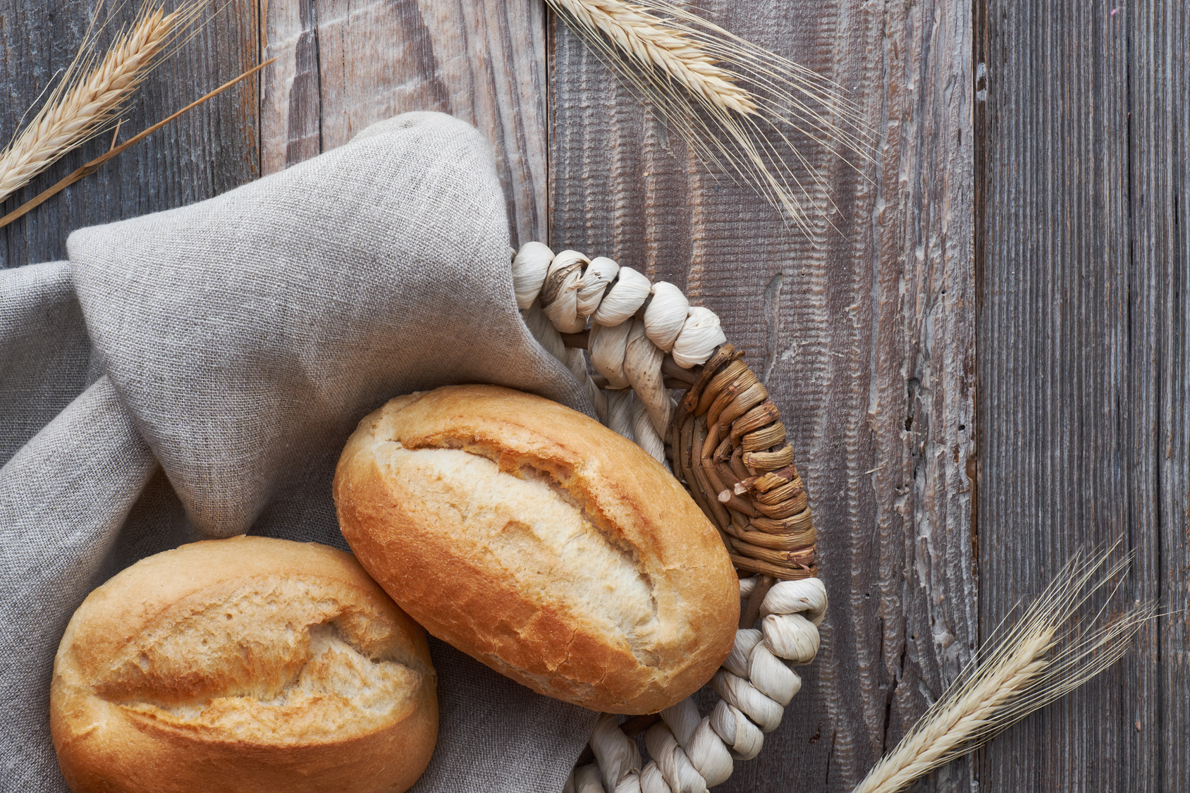 Warm dinner rolls piled in a cloth-lined basket on a rustic wooden table