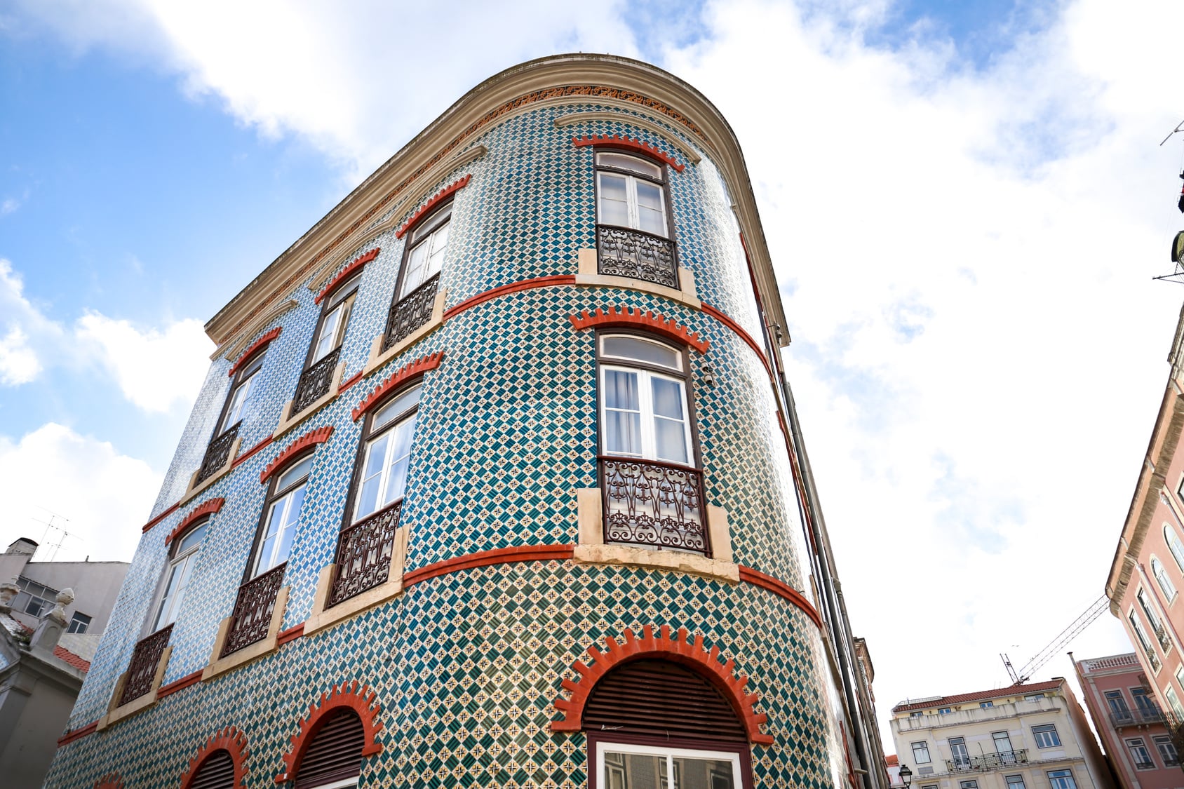 Steep Lisbon street with colourful tiled house facades and calcada cobblestone paving