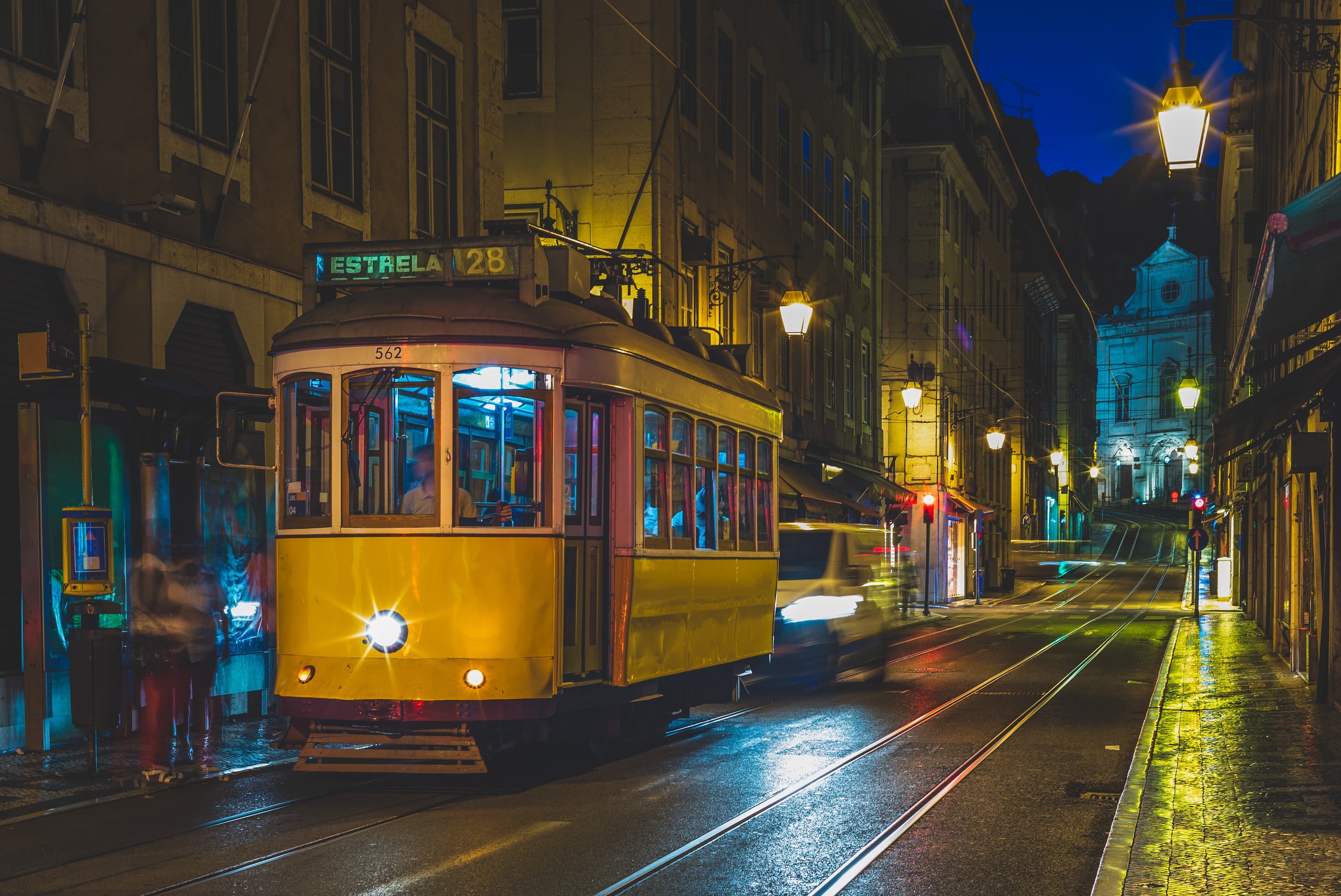 Tram 28 on a narrow Lisbon street at night during the busy June festival season