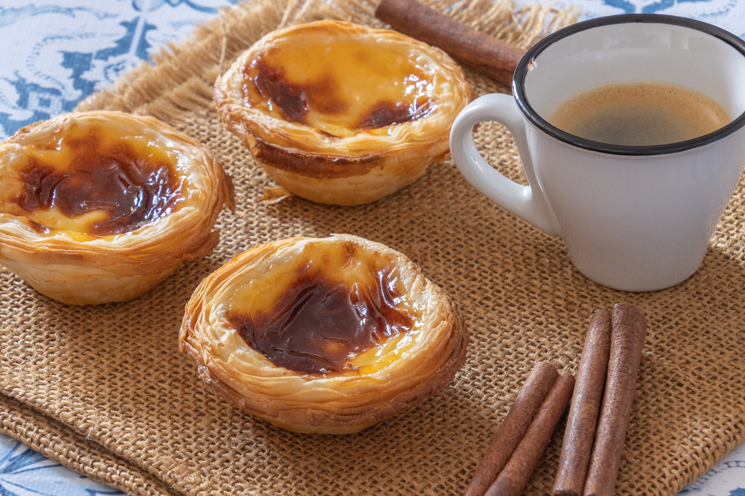 A pastel de nata and a small cup of coffee on a cafe table in Portugal
