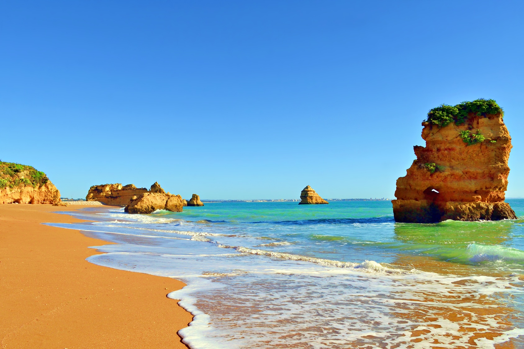 Golden cliffs and clear turquoise water at Praia da Dona Ana beach in Lagos, Algarve, Portugal