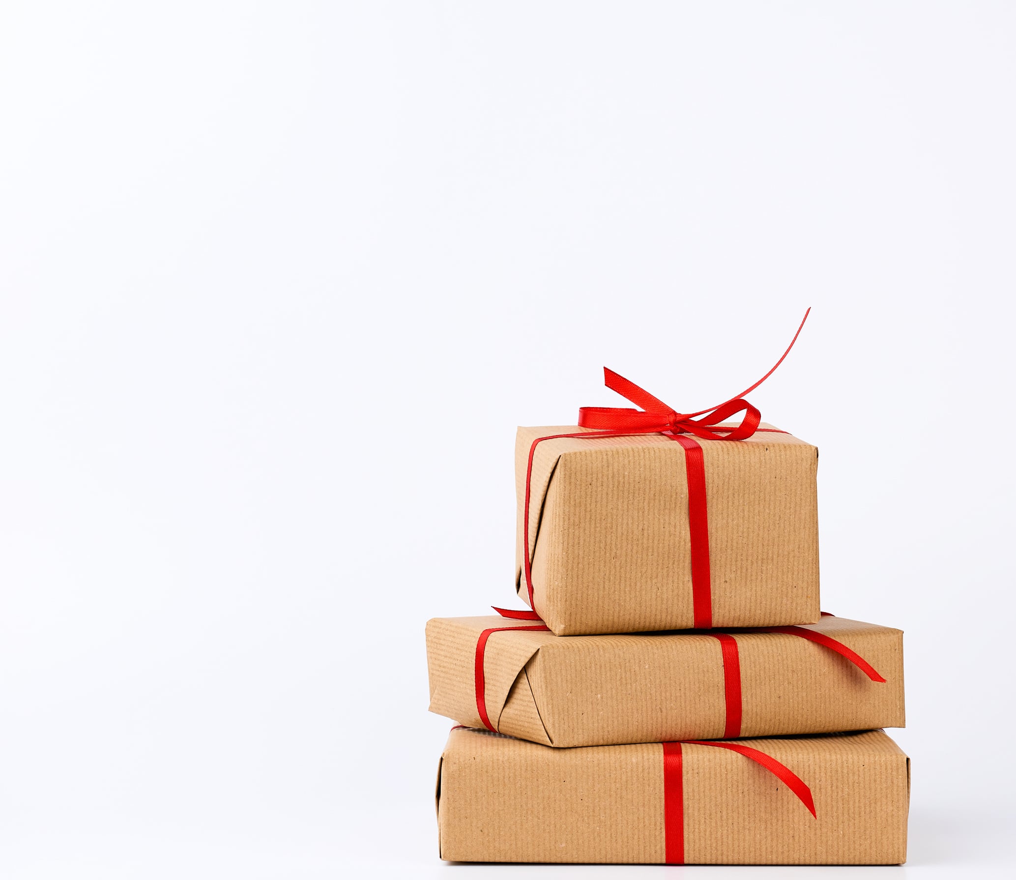 A stack of gifts wrapped in plain brown kraft paper and tied with ribbon