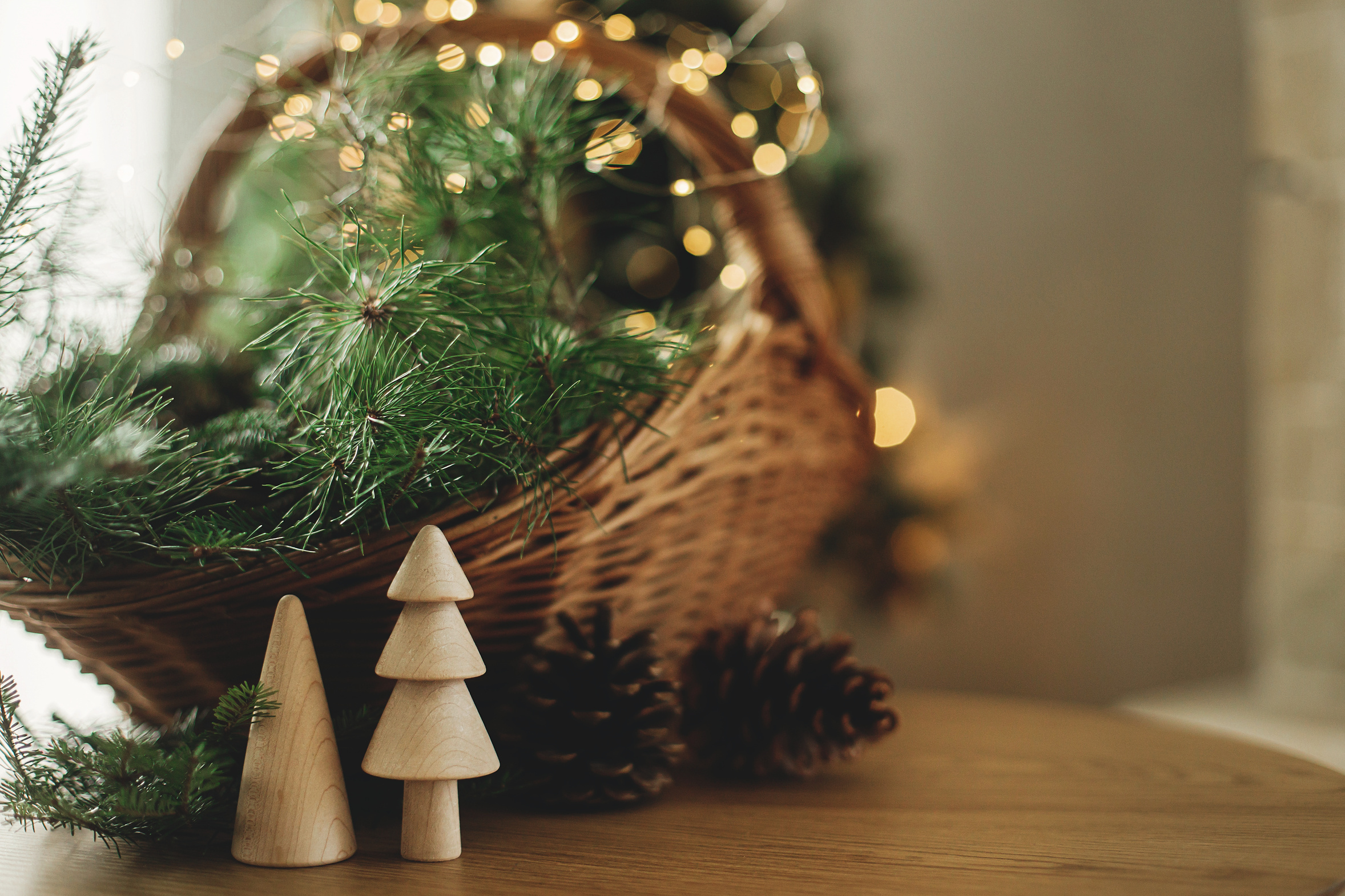 A basket of fir branches and pine cones beside a lit fireplace, simple holiday decorating
