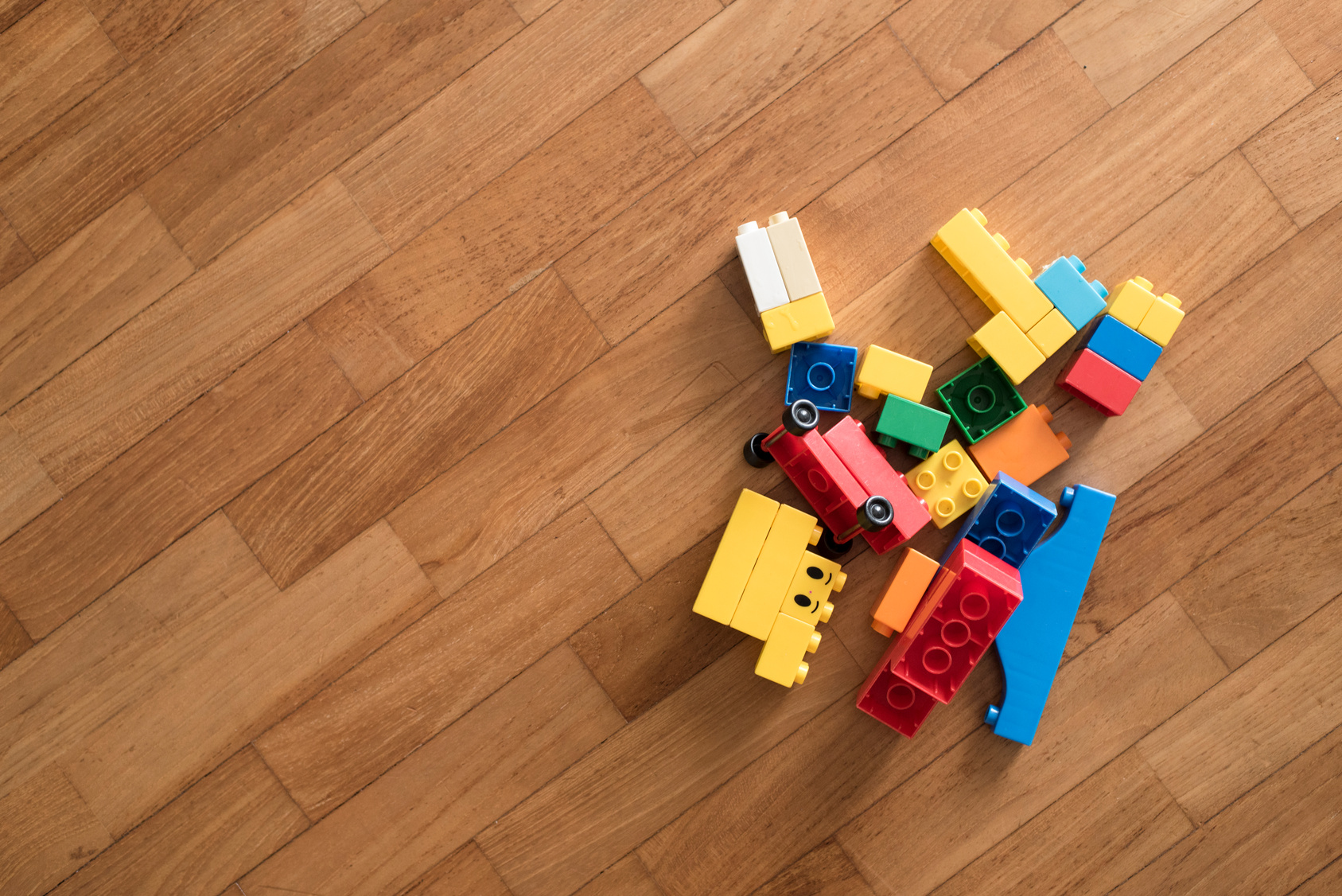 A small handful of wooden building blocks on a wooden floor after a toy rotation